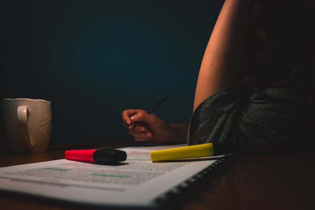 Close-up of hands analyzing a printed news article with a magnifying glass and highlighter